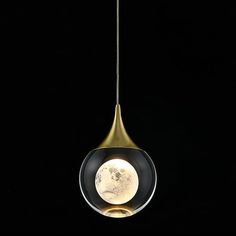 a black and gold colored light hanging from a metal pole with a white moon in the center