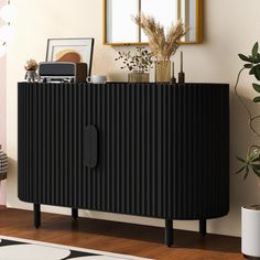 a black cabinet sitting on top of a wooden floor next to a potted plant