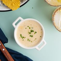 a white bowl filled with soup next to tortilla chips on a blue surface