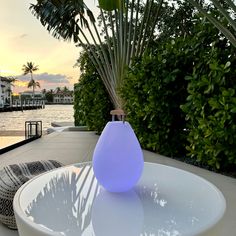 a large white vase sitting on top of a table next to a body of water