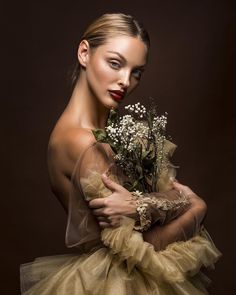 a woman in a tutu with flowers on her chest and hands behind her back