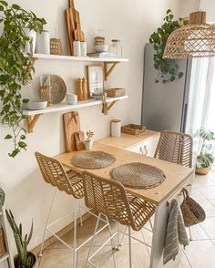 a dining room table and chairs with plants on the shelves