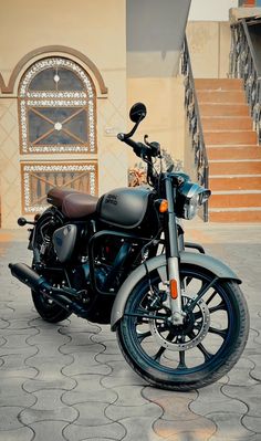 a black motorcycle parked in front of a building with steps leading up to the door