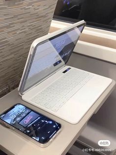 an open laptop computer sitting on top of a table next to a cell phone and tablet