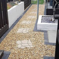 a cat sitting on top of a wooden bench next to a gravel path in front of a building