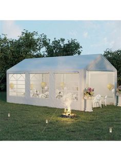 a white tent set up in the middle of a field with tables and chairs around it