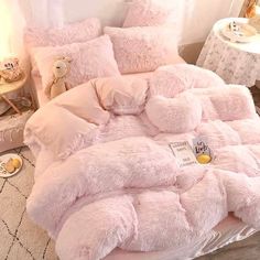 a bed with pink fluffy comforters and pillows