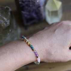 a woman's arm with a bracelet made out of glass beads and colorful stones