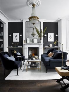 a living room filled with furniture and a fire place under a chandelier hanging from the ceiling