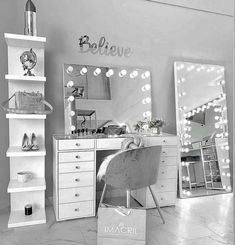 a black and white photo of a bedroom with lights on the wall, mirror, desk and chair