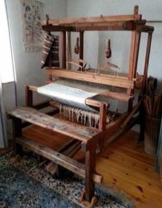 an old weaving machine is on display in a room with wood floors and blue rugs