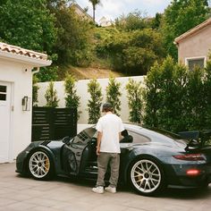 a man standing next to a black sports car