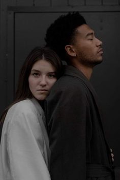 a man and woman standing next to each other in front of a door with their eyes closed