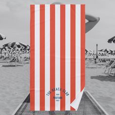 an orange and white striped towel sitting on top of a beach