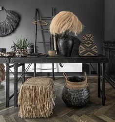 a table topped with vases and plants on top of wooden floor next to wall