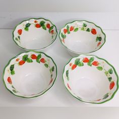 four white and green bowls with strawberries painted on the rims are sitting next to each other