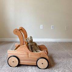 a small wooden toy car with a teddy bear in it's seat on the carpet