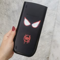 a hand holding up a cell phone with an evil face on the front and red eyes