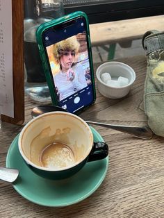 a cup of coffee sitting on top of a saucer next to a cell phone