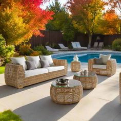 an outdoor living area with wicker furniture and pool in the backround, surrounded by fall foliage