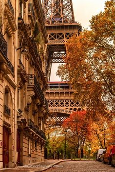 the eiffel tower in paris, france is seen from an alleyway with parked cars