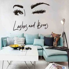 a living room with a blue couch and wall decal that says lashes and brows