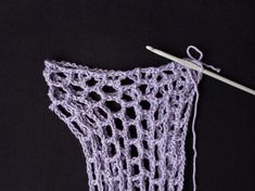 a crocheted object with a knitting needle next to it on a black surface