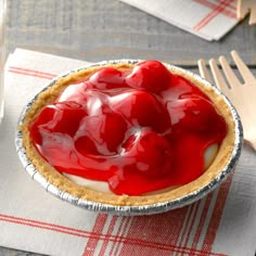 a pie with cherries on top is sitting on a napkin next to a fork