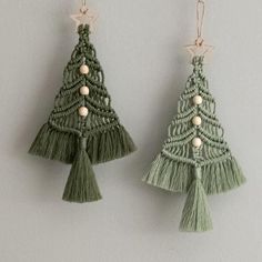 two green christmas trees with tassels hanging from them