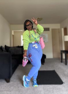 a woman in green shirt and blue pants holding a pink cup while standing on carpet