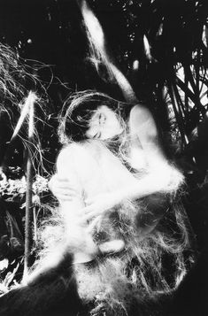 a black and white photo of a woman in the woods