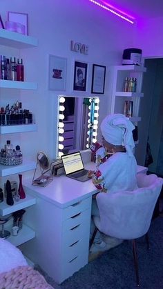 a woman sitting at a desk in front of a laptop computer on top of a white counter