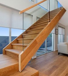 there is a wooden stair case in the living room with glass railings on both sides