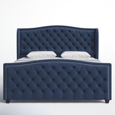 an upholstered blue bed with white pillows