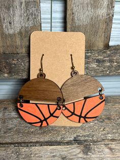 two wooden hoop earrings with basketballs painted on the front and back, hanging from hooks