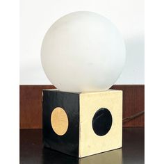 a white ball sitting on top of a wooden block next to a black and white box