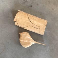 two wooden spoons sitting next to each other on the floor in front of a piece of wood