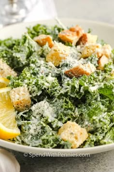 a white bowl filled with salad and lemon wedges