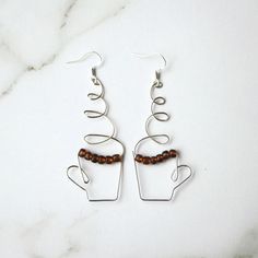 a pair of silver earrings with brown beads on them sitting on a marble counter top