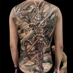 the back of a man's body with tattoos on it and an image of a demon