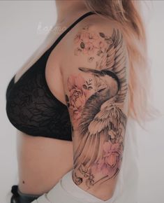 a woman's arm with a bird and flowers tattoo on her left side shoulder