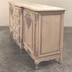 an old dresser is painted white and has ornate carvings on the doors, drawers, and sides