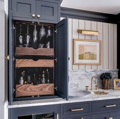 an open cabinet in the middle of a kitchen with marble counter tops and gold handles