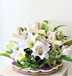 a basket filled with white flowers on top of a wooden table next to a cross