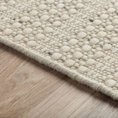 a close up view of a rug on the floor with wood and white carpeting