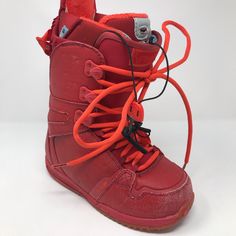 a pair of red snowboard boots with orange laces