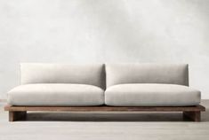 a white couch sitting on top of a wooden frame in front of a gray wall