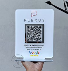 a person holding up a qr - code for the googleplexus logo in front of a gray wall