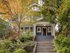 a house with steps leading up to the front door and trees in fall colors around it