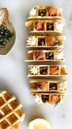 several waffles are stacked on top of each other with olives and salmon